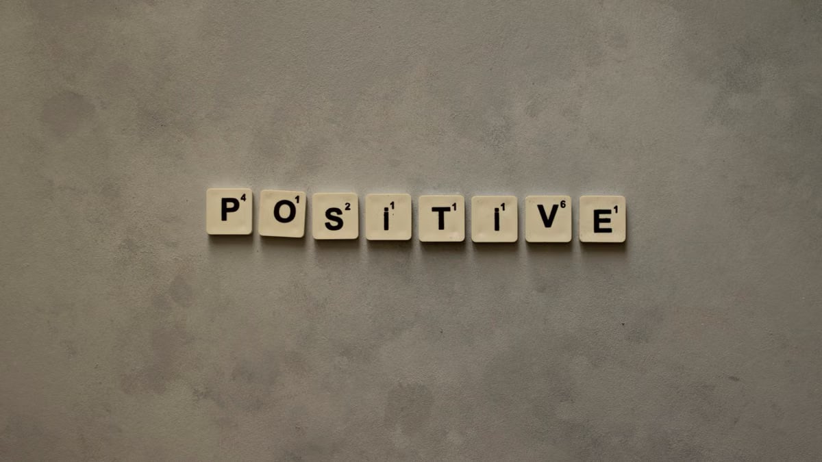 Scrabble tiles spelling 'Positive' on a textured surface, conveying optimism.